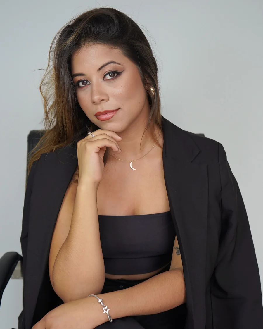 Amanda Lopes sentada, mão no queixo